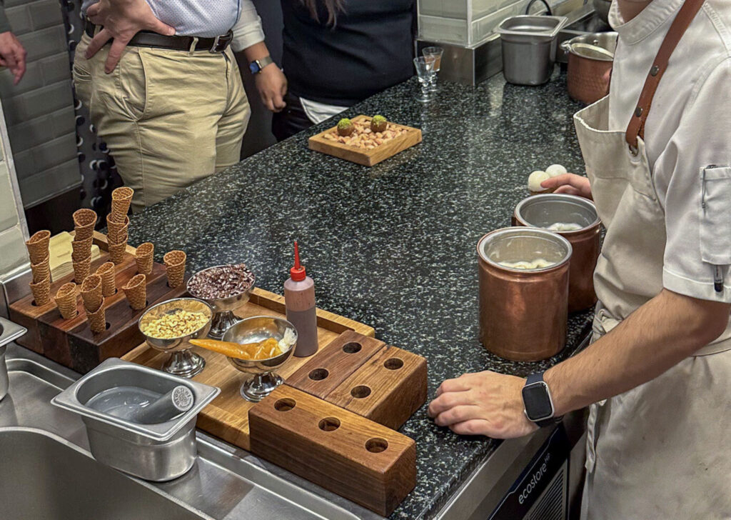Cooks working at the kitchen counter with wooden stands of cones and small bowls of garnish