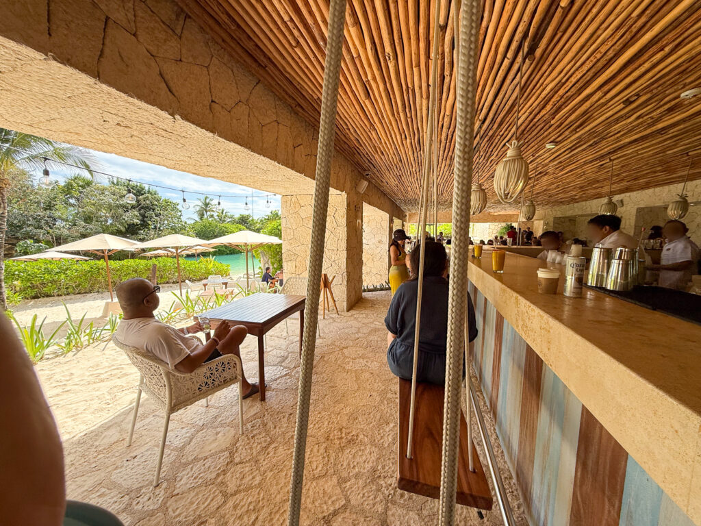 The open side of the bar under its reed ceiling, loungers and the pool beyond