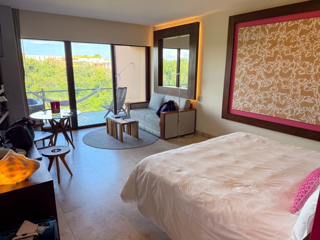 A bed against a patterned headboard, glass doors open to the jungle