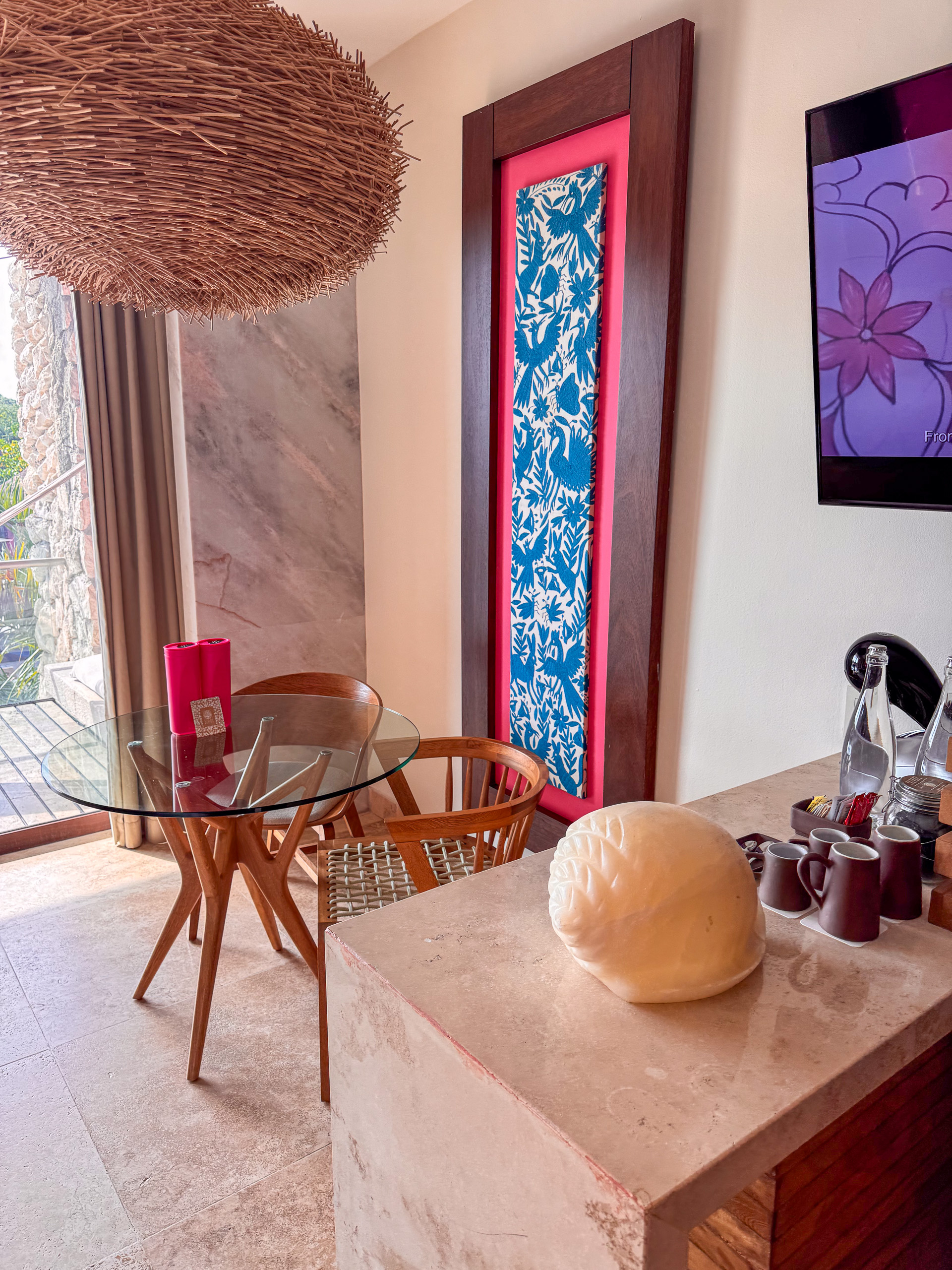 A woven pendant lamp over the desk, the room's colours picked up in the art