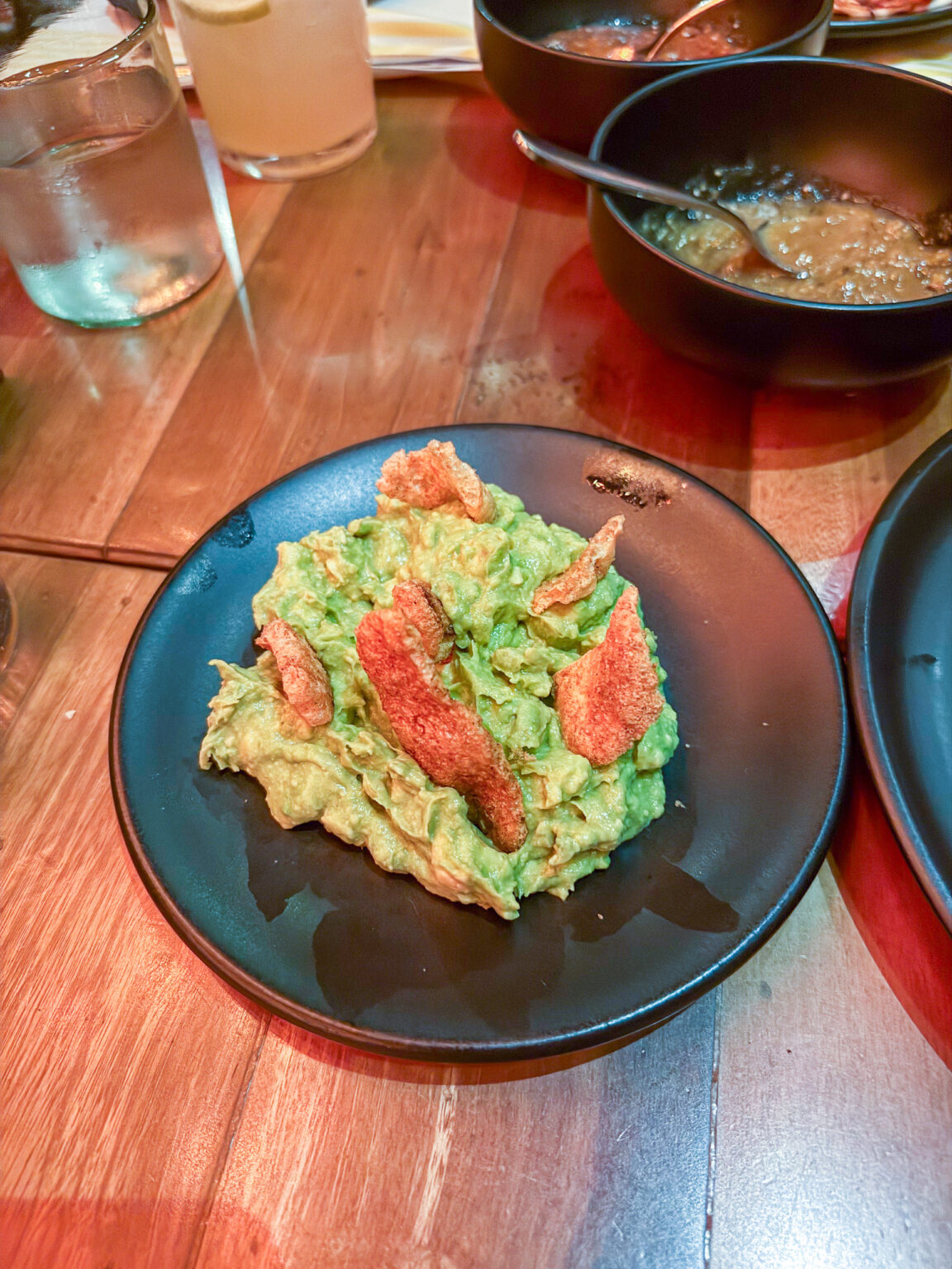 Smashed avocado dressed with grapefruit on a dark plate