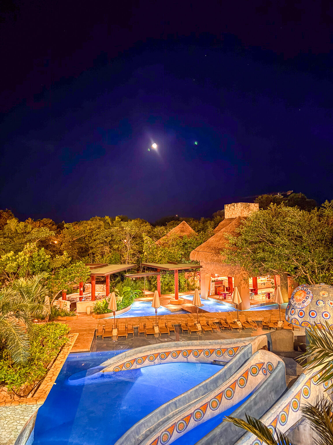 The pools lit from within under a clear night sky