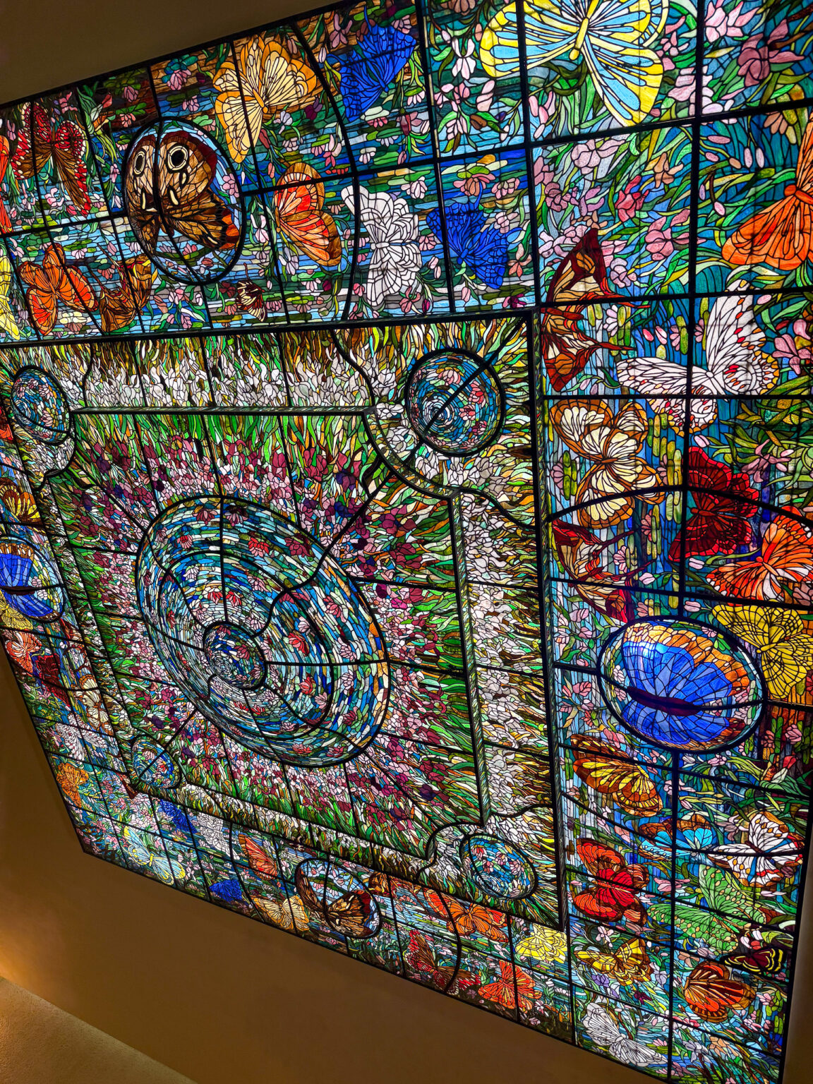 A tall stained-glass window in bright abstract colours