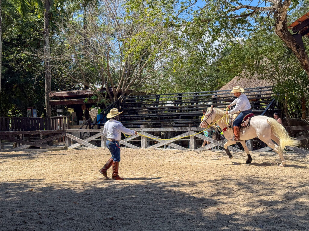 Riders in charro dress working horses in a sand corral