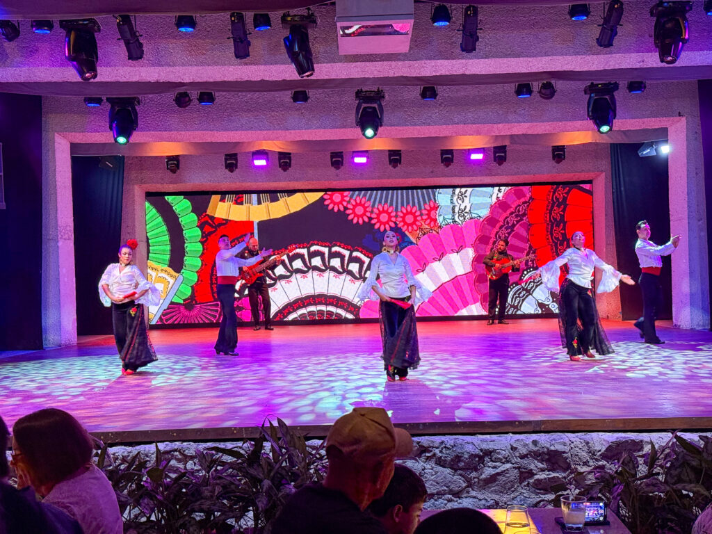 The company in white forming a fan of colour across the stage