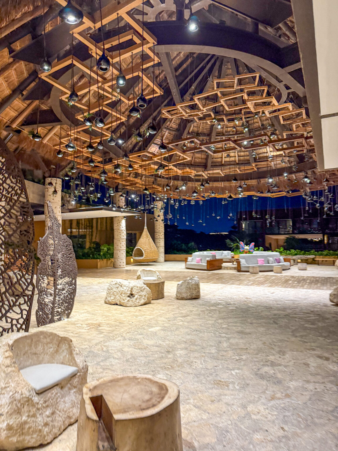 A lounge under a timber lattice ceiling, stone seats on a pale floor