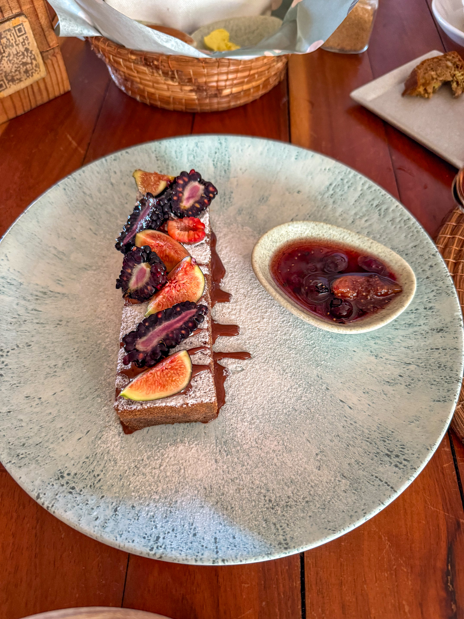 A dessert of figs and berries along a pale plate with a dish of compote