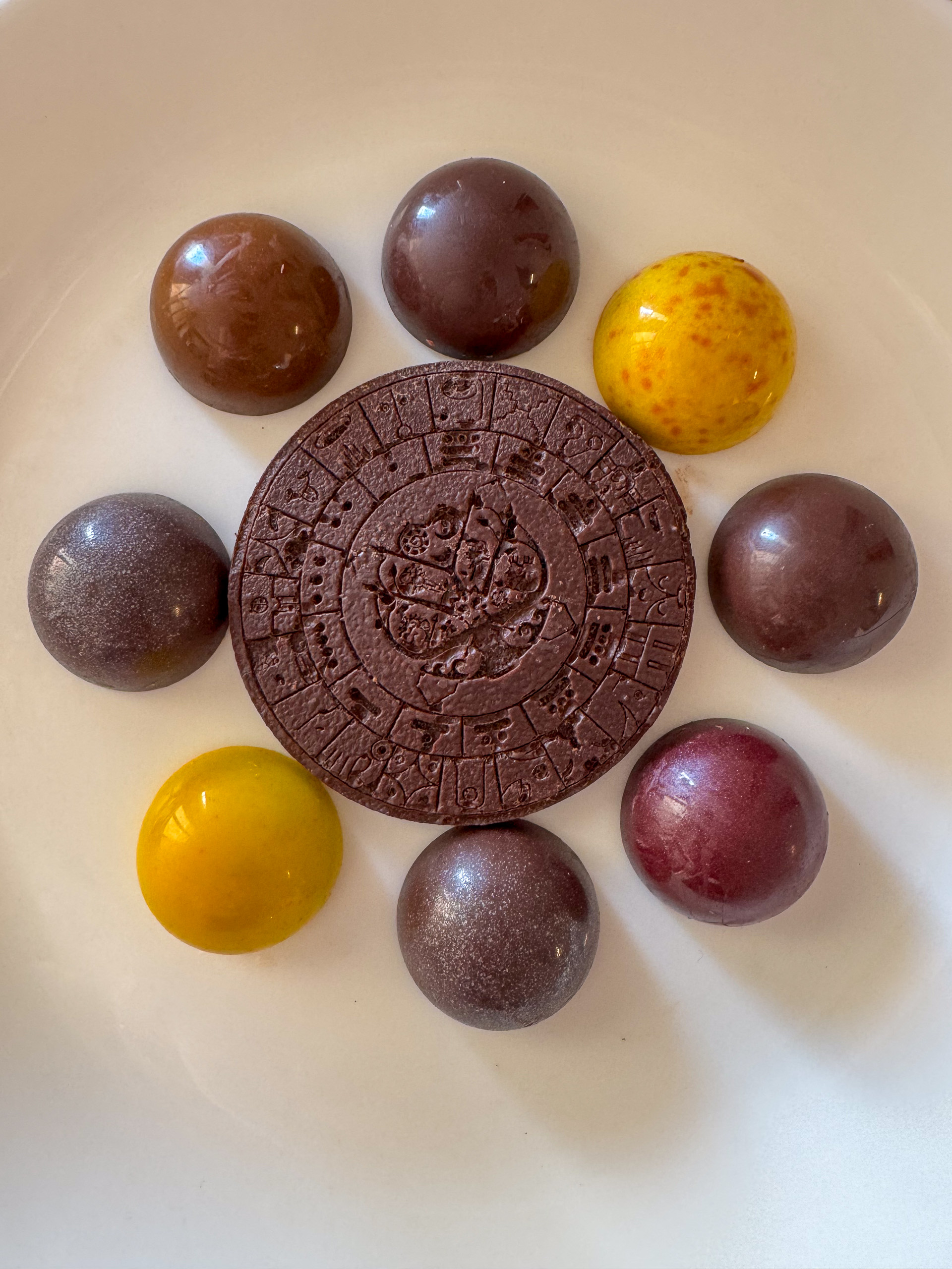 Chocolate spheres set round a stamped disc on a white plate