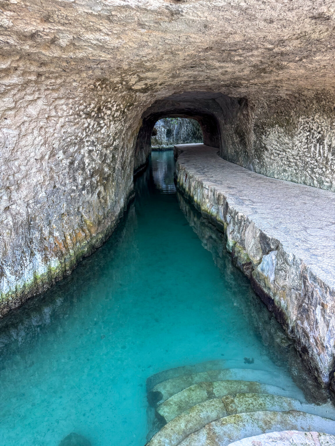 Turquoise water running through a low limestone tunnel
