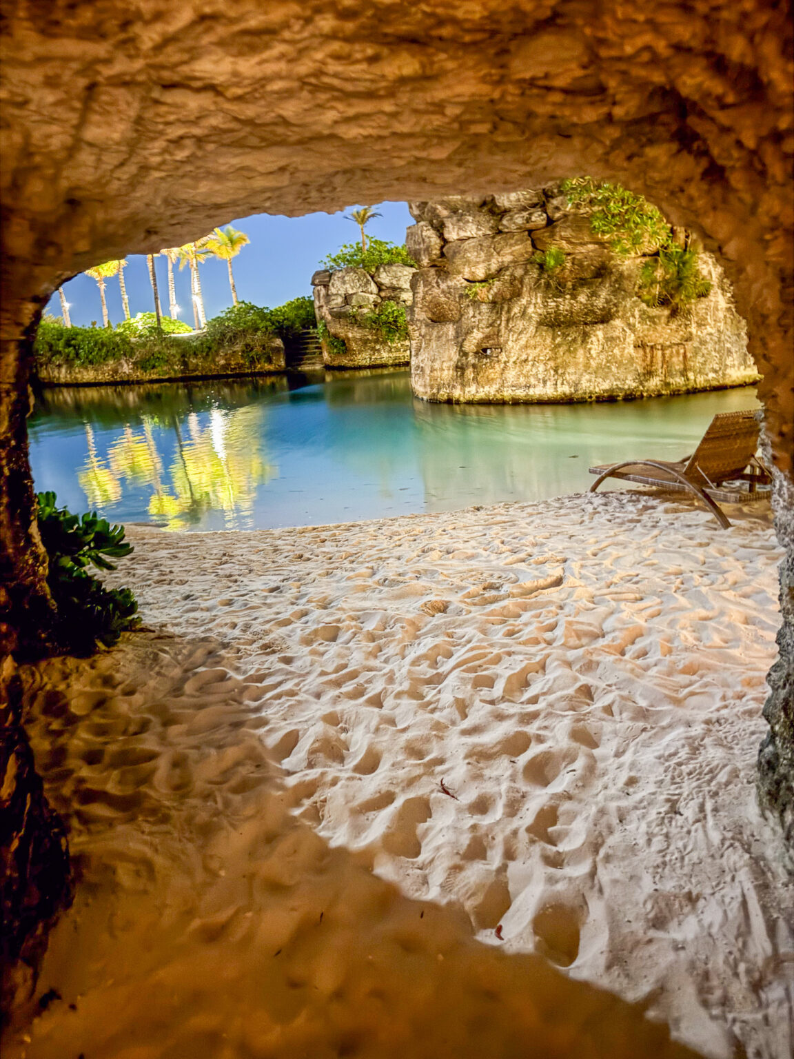 A cave mouth opening onto white sand and blue water