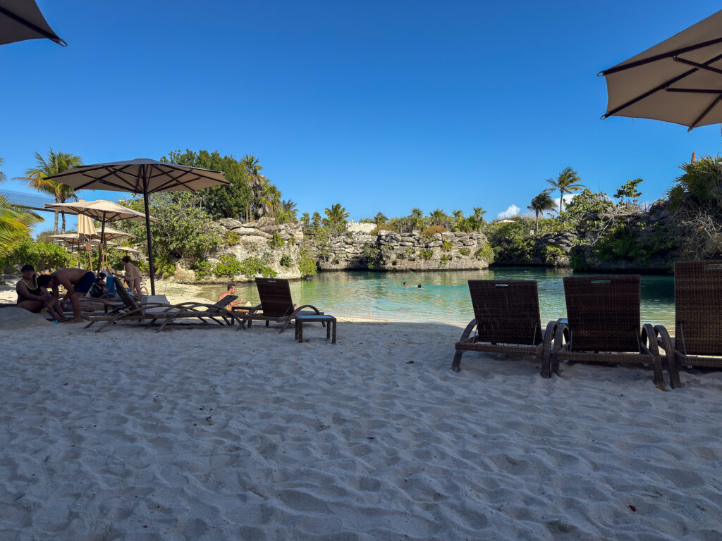 Loungers and umbrellas on the sand beside the turquoise inlet